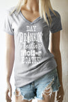 A blonde model standing wearing a heather grey v-neck t-shirt with the words in white Day Drinkin' Floatin' & Motor Boatin' and shredded cut off shorts